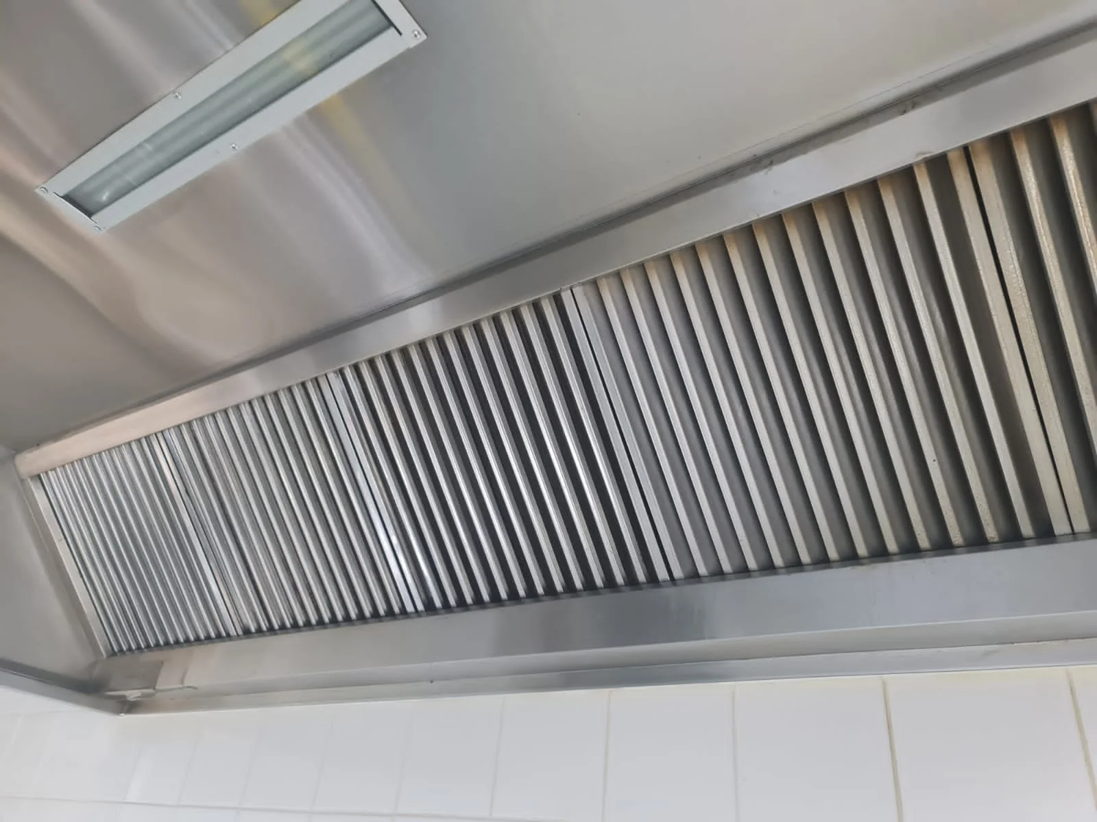 Close-up of a grease-coated kitchen exhaust fan and filter before cleaning